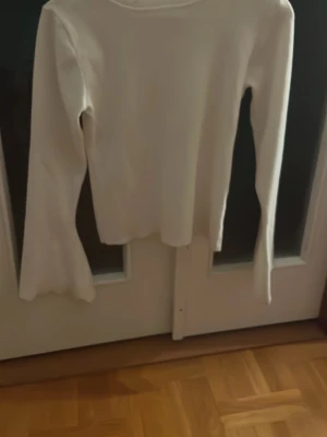 Vit långärmad tröja by clara - Vit långärmad tröja från Missäy med utsvängda ärmar och rund halsringning. Tröjan är enkel och stilren, perfekt att matcha med jeans eller kjol. Mjukt material som känns skönt mot huden. Har aldrig använt den. 