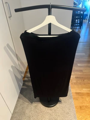 Svart midikjol  - En stilren svart midikjol. Kjolen har en rak och enkel design som ger en elegant look. Perfekt för dig som gillar klassiska plagg med en modern touch.