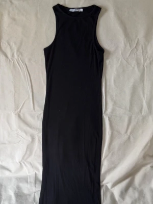 Svart ribbad maxiklänning NA-KD - Svart ribbad vadlång klänning från NA-KD med ärmlös design och rund halsringning. 