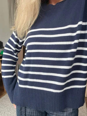 Marinblå randig stickad tröja Papaya - Säljer en marinblå stickad tröja från Papaya i storlek M. Tröjan har vita horisontella ränder, rund halsringning och ribbade muddar vid ärmslut och nederkant. Perfekt för en avslappnad och stilren look.
