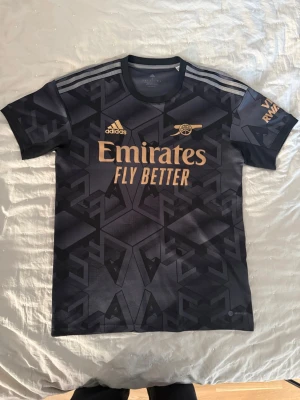 Arsenal bortatröja 22/23 - Säljer denna riktigt snygga Arsenal tröja från säsongen 22/23 för ett fint pris. Den är äkta och köpt från adidas. Storlek S. Riktigt bra skick 10/10. Vid funderingar är det bara att fråga!