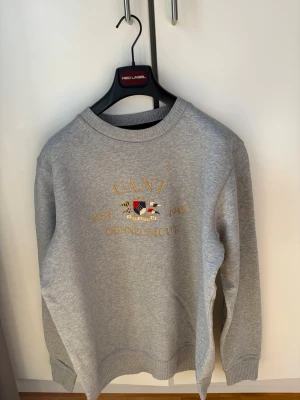 GANT Shield Crewneck - Denna fantastiska gråa GANT Crewneck är en perfekt tröja för dig som gillar klassisk och stilig stil. Tröjan är som helt ny och säljs då den är för stor. (Stor XL) 🎉Tröjan köpt på Boozt för 1099 kronor på rea från 1695 kronor ordinarie pris därav pris! 🎉För mer info skriv dm!