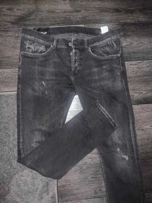 Svarta dondup jeans george med slitningar - Väldigt snygga svarta dondup jeans med slitningar i storlek 33 i nyskick. Ytterbenslängd  längs hela sidan 101cm, benöppning vid foten 15cm, innerlängd 75cm, höft till höft är den 43 cm. 