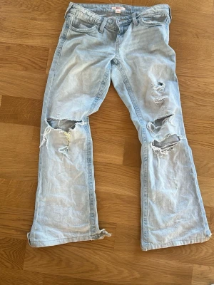 Ljusblå slitna jeans Gina Tricot XS - Säljer ett par ljusblå jeans från Gina Tricot i storlek XS. Jeansen har flera slitningar och hål på benen för en trendig, avslappnad look. Klassisk femficksmodell med raka ben och bälteshällor. Perfekta för dig som gillar en edgy stil.