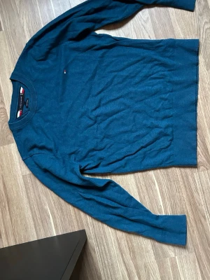 Blå stickad tröja Tommy Hilfiger - Snygg blå stickad tröja från Tommy Hilfiger med rund halsringning och diskret logga på bröstet. Tröjan har ribbade muddar vid ärmslut och hals, och är tillverkad i ett mjukt material med 'Luxury Touch'-känsla. Perfekt för dig som gillar stilrena plagg. Nypris 1499 kr, inköpt på Zalando.