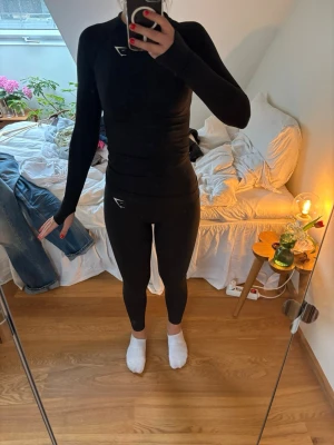 Svarta seamless leggings från Gymshark - Säljer ett par svarta seamless leggings från Gymshark med hög midja och diskret logga på höften. Stretchigt och bekvämt material som sitter tight och formar sig efter kroppen. Perfekta för träning eller chill. Snygg och stilren design.