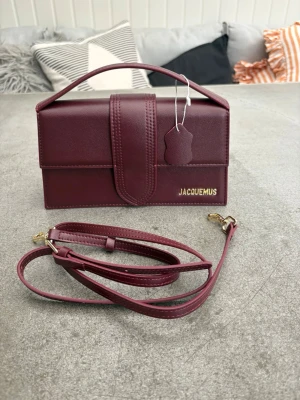 Jacquemus Bambino Väska Vinröd / Burgundy - Säljer nu min schyssta Jacquemus bambino väska! Den är i vinröd/burgundy färg. Aldrig använd, köpte åt min tjej men det var inte för henne… ✅Nyskick✅ Band medföljer, ❗️Självklart äkta❗️