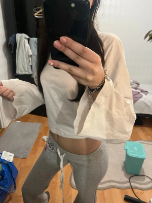 Vit croppad blus med vida ärmar - Säljer en vit croppad blus med långa, vida ärmar och lätt transparent material. Toppen har en avslappnad passform och är perfekt för en trendig och stilren look.