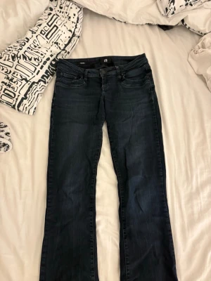 Mörkblå bootcut jeans - Säljer ett par mörkblå bootcut jeans med klassisk femficksdesign och normal midja. Jeansen har lätt slitna detaljer vid bensluten och är tillverkade i stretchigt denimtyg för skön passform. Perfekta för dig som gillar en avslappnad men ändå trendig look. w26 l34