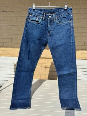Levi's blå raka jeans. 511 - Klassiska blå jeans från Levi's med rak passform och fem fickor. 511 i stl 31/32. Jeansen har en djupblå tvätt, synliga nitar och Levi's ikoniska läderpatch bak i midjan. Dragkedja i gylfen. Superskick!