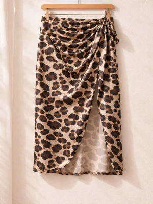 Leopardmönstrad omlottkjol med slits - Snygg leopardmönstrad omlottkjol i satinliknande material med hög slits och knyt i midjan. Kjolen har en beige bas med mörkbruna och svarta fläckar, vilket ger en trendig look. Perfekt för dig som vill sticka ut med en cool och djärv stil.