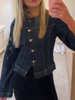 Mörkblå jeansjacka med sned knäppning - Skit snygg mörkblå jeansjacka med sned knäppning och markerade sömmar. Perfekt till sommaren🥹🌷