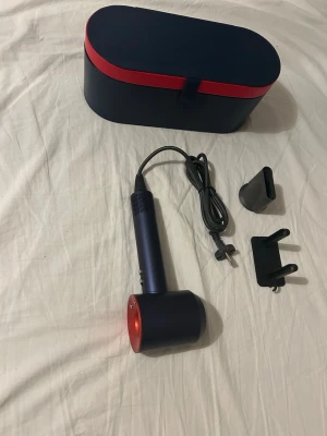 Blå och röd hårfön - Blå och röd dyson hårfön. Helt ny, ej använd. Kommer med tillbehören på bilden samt lådan i bilderna