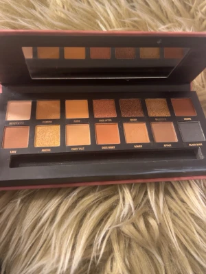 W7 Romanced ögonskuggspalett - W7 Romanced ögonskuggspalett med 14 nyanser i varma, neutrala toner som beige, guld, koppar, brunt och svart. Paletten har både matta och skimriga skuggor i rektangulära pans, perfekt för att skapa olika looks!