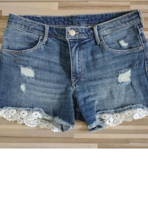 Jeansshorts med spetskant - Supersöta mörkblå jeansshorts från hm med spetskant och slitningar. Inte superlågmidjade men dom är jättesnygga om man viker ner dom!