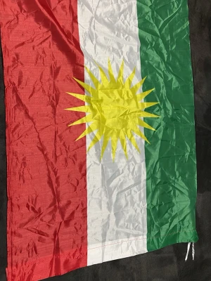 Kurdisk flagga, den är skrynklig för den har varit iväg lagd, går bra att använda typ plattång för o göra den rak har gjort de förut funkade perfekt.  - Kurdisk flagga i tyg med vertikala fält i rött, vitt och grönt samt en gul solsymbol i mitten. Flaggan har rektangulär form och är försedd med snören för upphängning. Perfekt för att visa kurdisk identitet eller dekorera rummet.