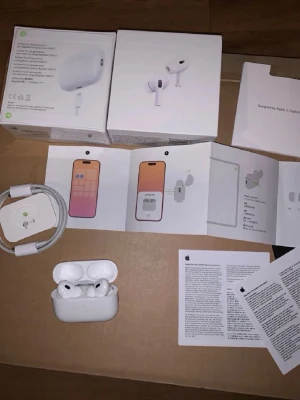 Apple AirPods Pro 2 - Säljer ett par vita Apple AirPods Pro (2nd Gen) med MagSafe-laddningsetui. Trådlösa in-ear hörlurar i stilren design med silikonproppar och touchkontroller. Levereras med originalkartong, laddningskabel och manualer. Perfekta för musik, samtal och träning.