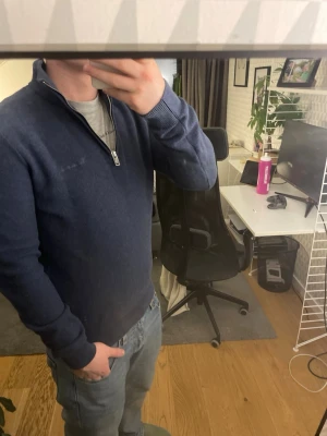 Mörkblå halvzip tröja - Mörkblå stickad tröja med halv dragkedja och hög krage. Tröjan har långa ärmar och ribbade muddar vid ärmslut och nederkant. Perfekt för lager på lager och enkel att matcha med jeans.