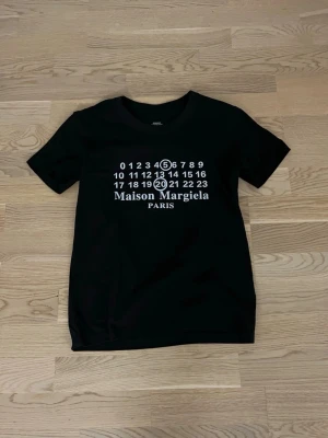 Maison Margiela svart t-shirt - Svart t-shirt från Maison Margiela. Klassisk rund krage. Skön passform och 100%  bomull. Perfekt för dig som gillar stilrena designer.
