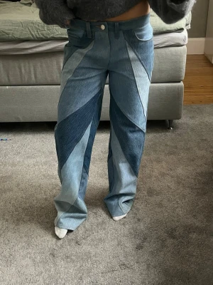 Patchwork jeans i olika blå nyanser - Unika patchwork jeans med flera olika blå nyanser i coolt mönster. Raka ben och medel låg midja. Perfekta för dig som vill sticka ut med din stil. Tillverkade i klassisk denim.