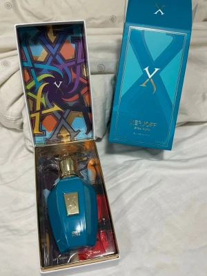 Xerjoff Erba Pura Eau de Parfum 100ml - Lyxig parfym från Xerjoff i doften Erba Pura. Flaskan är turkosblå med gulddetaljer och har en elegant, geometrisk form. Kommer i en färgstark och exklusiv förpackning med grafiskt mönster. Perfekt för dig som gillar unika och exklusiva dofter.