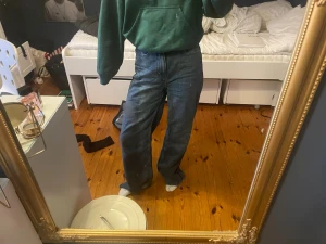 Blåa wide leg jeans med hög midja - Säljer ett par blåa jeans med wide leg-modell och hög midja. Jeansen har klassisk femficksdesign och raka, vida ben som ger en avslappnad och trendig look. Perfekta för dig som gillar en loose fit-stil.