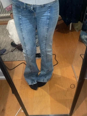 Ljusblå raka jeans med sömdetaljer - Säljer ett par ljusblå jeans från monki med raka ben och markerade sömmar framtill. Jeansen har klassisk femficksmodell, bälteshällor och dragkedjegylf. Materialet är denim i bomull och benen har råa, avklippta kanter för en trendig look.