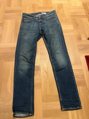 Tiger of sweden slim fit - Snygga blå jeans med rak passform och klassisk femficksdesign. Jeansen har en lätt tvättad look med subtila slitningar vid knän och lår. Perfekta för en avslappnad stil och tillverkade i denim. Stängs med dragkedja och knapp.
