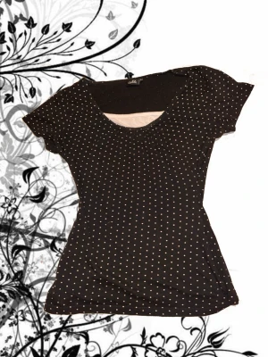 Svart prickig topp med rund hals - Svart topp med vita små prickar över hela plagget. Tunn och mjuk i materialet. omsydd så har några charmiga karaktärsdrag 