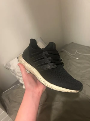 Svarta Adidas Ultraboost sneakers - Svarta Adidas Ultraboost sneakers med stickad ovandel och klassisk Boost-sula i vitt. Skorna är i storlek 40 2/3 och är 100% äkta men är slitna och är trasiga på framsidan. Hör av er ifall ni har frågor eller är intresserade!🙌 Priset går att diskutera. Ordinarie pris 2000kr