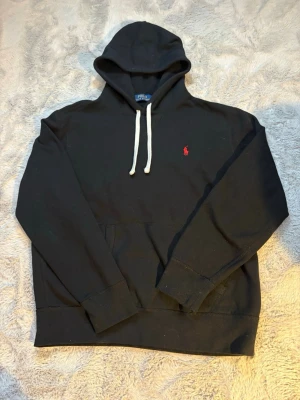 Svart hoodie från Polo Ralph Lauren -  Svart  Polo Ralph Lauren hoodie i storlek M . Inga defekter, skavanker eller något liknande. Hoodien är i mycket bra skick. Nypris 2599kr vårt pris 899kr