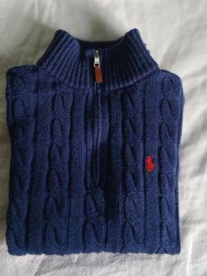 Marinblå kabelstickad tröja Polo - Hej!! Säljer en jätte snygg och super stilig kabelstickad Ralph lauren halfzip. Den har en jättefin mörkblå färg och är i otroligt bra skick. Den har även en QR kod som visar att den är äkta på lappen. Storlek emellan S/M beronde på lite hur man vill ha den. Dessutom så är den varm och super mysig som gör den perfekt för tider som nu!! Priset är redan prutat men det går att förhandla. Skriv såklart om ni har fler frågor eller funderingar!!:)