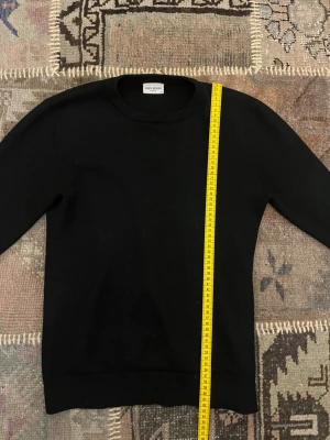 Svart merino ull tröja  - 100% merino ull tröja från john henric. Är 175 cm på bilden. Längd är 62 cm och ärmen är 55 cm lång. Har lagats i armhålorna men syns inte alls