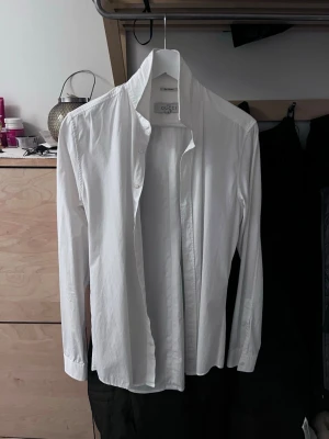 Vit skjorta från Gucci - Klassisk vit skjorta från Gucci i stilren design. Skjortan har lång ärm, knäppning framtill och en snygg krage. Tillverkad i ett tunt och mjukt material som känns lyxigt mot huden. Perfekt för dig som gillar exklusiva märken och enkel, clean stil.