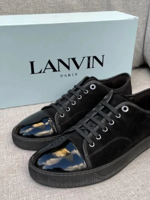 Lanvin sneakers  - Snygga svarta sneakers från Lanvin med ovandel i mocka och glansig lackad tå. Skorna har svarta skosnören, metallfärgade öljetter och en svart sula. Perfekta för dig som gillar stilrena och exklusiva detaljer. Bara skorna ingår. Nypris 5000kr - mitt pris 2300kr 
