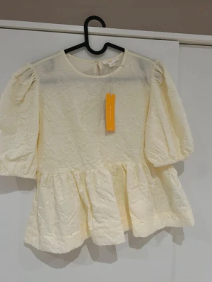 Peplumblus - Vit/ creame färgad peplumtopp med volang underdel 