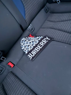 Burberry svartvit logomössa - Säljer en snygg svartvit mössa från Burberry med tydlig logga på uppviket och ett grafiskt mönster över hela mössan. Perfekt accessoar för dig som gillar streetstyle och vill sticka ut med ett exklusivt märke. Materialet känns mjukt och stretchigt.