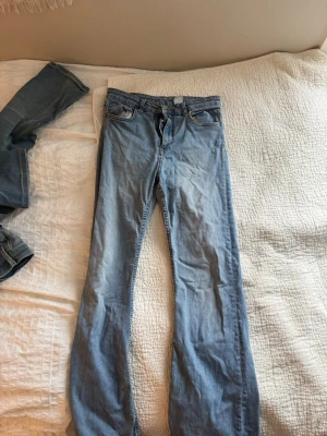 Ljusblå bootcut jeans från H&M - Säljer ett par ljusblå bootcut jeans från H&M i klassisk denim. Jeansen har fem fickor, normal midja och är tillverkade i bomullsmaterial. Perfekta för en avslappnad och trendig look.