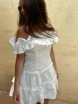 Vit offshoulder klänning med volang  - Populär och eftertraktad vit klänning med offshoulder och volangdetaljer. Perfekt för sommaren och till studenten🌸