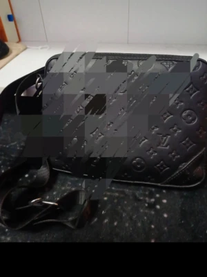 Svart axelväska Louis Vuitton - Snygg svart axelväska från Louis Vuitton i präglat läder med det klassiska monogrammönstret. Väskan har justerbar axelrem i textil och detaljer i svart metall. Perfekt för dig som vill ha en stilren och lyxig accessoar.