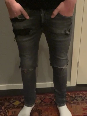 Svarta jeans från dondup, stl 30 - Tjena dessa jeans är från dondup och passar perfekt för dig som vill ha lite klass i din stil. Dem har lite slitningar runt benen och är lite mörk grå. 