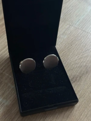 Manschettknappar i Stainless steel - Säljer ett par stilrena, runda manschettknappar. De har en slät och blank yta och kommer i en svart ask. Perfekta för att ge skjortan en elegant touch.