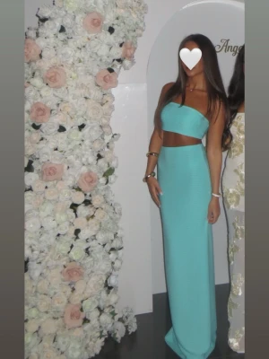 Turkos långklänning med bandeau - Säljer en snygg turkos långklänning med bandeau-topp och cut-out i midjan. Klänningen är ärmlös och har en tight passform som framhäver figuren. Perfekt för sommarens tillfällen när du vill sticka ut med en fräsch färg.