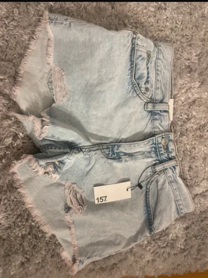 Lågmidjade ljusblå jeansshorts med slitningar - Korta lågmidjade jeansshorts från Lager 157 med lappen kvar. Säljs då dom va för små för mig💕💕
