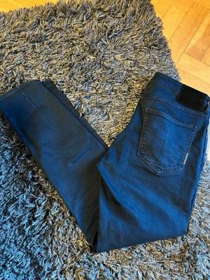 Neuw jeans - Snygga mörkblå slim fit jeans från Neuw med klassisk femficksdesign och svarta detaljer på bakfickan. Jeansen har en smal passform och är tillverkade i stretchigt denimtyg för extra komfort. Perfekta för en trendig och avslappnad look.