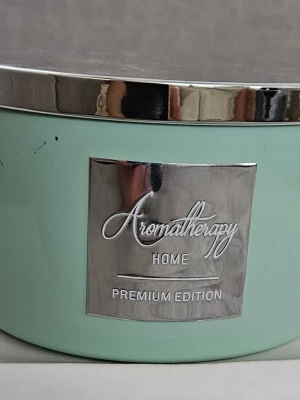 Aromatherapy Home doftljus grön - Snyggt doftljus från Aromatherapy Home Premium Edition i en ljusgrön glasburk med silverfärgat lock och metallskylt. Ljuset har tre vekar och passar perfekt för att skapa en mysig stämning hemma.