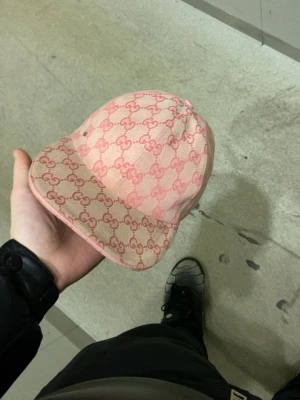 Rosa Gucci keps med monogram - Säljer en snygg rosa keps från Gucci med det klassiska GG-monogrammet över hela kepsen. Kepsen har böjd skärm och är tillverkad i ett slitstarkt tyg. Perfekt för dig som vill ha en exklusiv och trendig accessoar till din outfit. Pris går att diskutera ! Jag har även orderbekräftelse så den är äkta