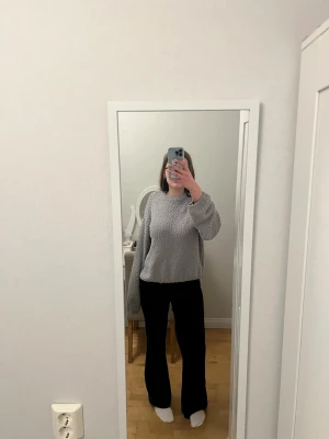 Grå fluffig stickad tröja - Mysig grå stickad tröja med fluffig textur och rund hals. Tröjan har långa ärmar och en avslappnad passform som ger en chill vibe. Perfekt för dig som gillar oversized och bekvämt. Materialet känns mjukt och gosigt mot huden.
