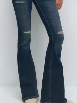 Mörkblå bootcut jeans med slitningar - NYPRIS: 399kr Snygga mörkblå bootcut jeans med slitningar på låren och knäna. Jeansen har en skön passform. Använt ett par gånger i höstas.