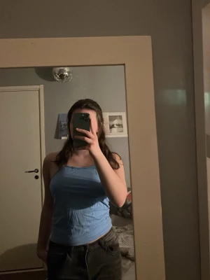 Ljusblå linnetopp med smala axelband - Säljer en ljusblå linnetopp med smala axelband. Toppen har en enkel och slim passform som sitter snyggt på kroppen. Perfekt för varma dagar och enkel att matcha med jeans eller shorts.